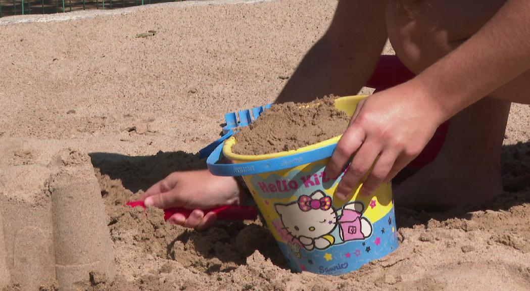 Una desena d'infants omplen la pista de vòlei platja amb castells de sorra